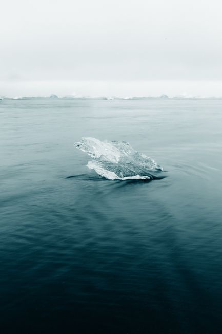 A lone iceberg floats peacefully on a calm winter sea, invoking serenity and solitude.