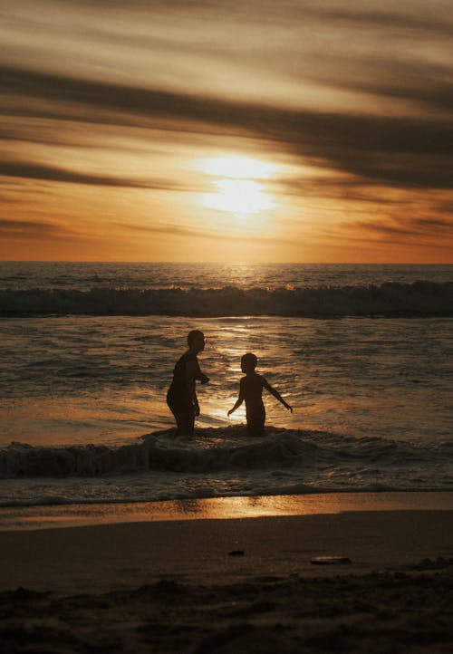 Mother Playing with Son on Sea Shore at Sunset
