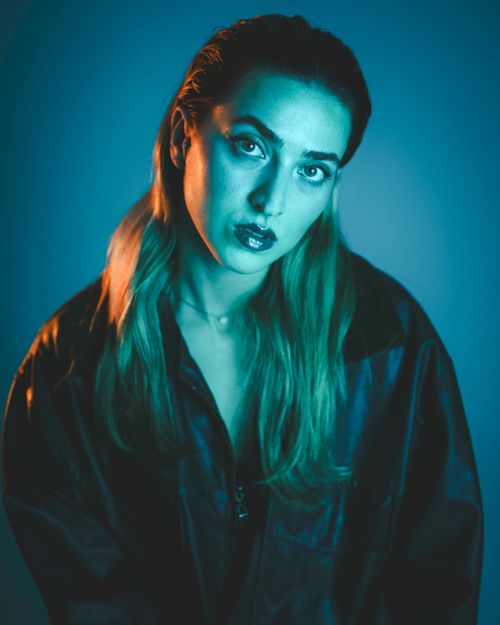 Free Fashion portrait of a woman in a leather jacket with blue lighting, exuding a modern and moody vibe. Stock Photo