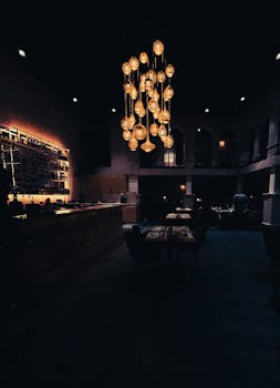 Cozy restaurant interior featuring elegant golden chandeliers and a dimly lit ambiance with a stylish bar area.
