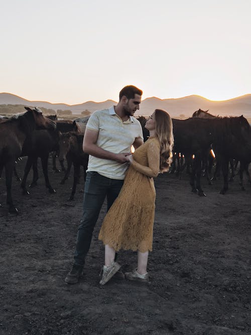 Couple by Herd of Horses at Sunrise