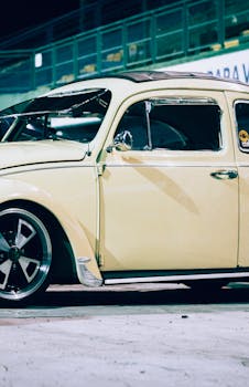Classic yellow vintage car showcased under night lights, highlighting retro design.