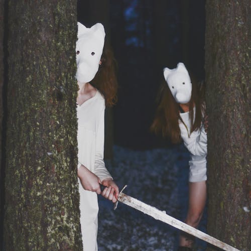 People in Masks and with Sword in Forest at Night
