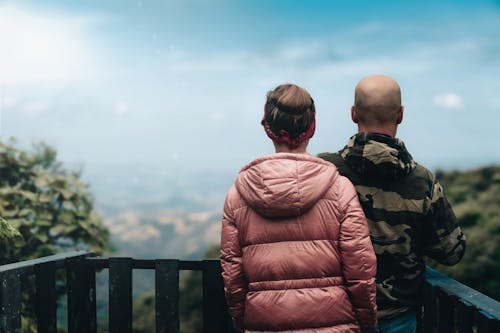 Back View of a Man and Woman Standing at an Observation Deck on a Hill 