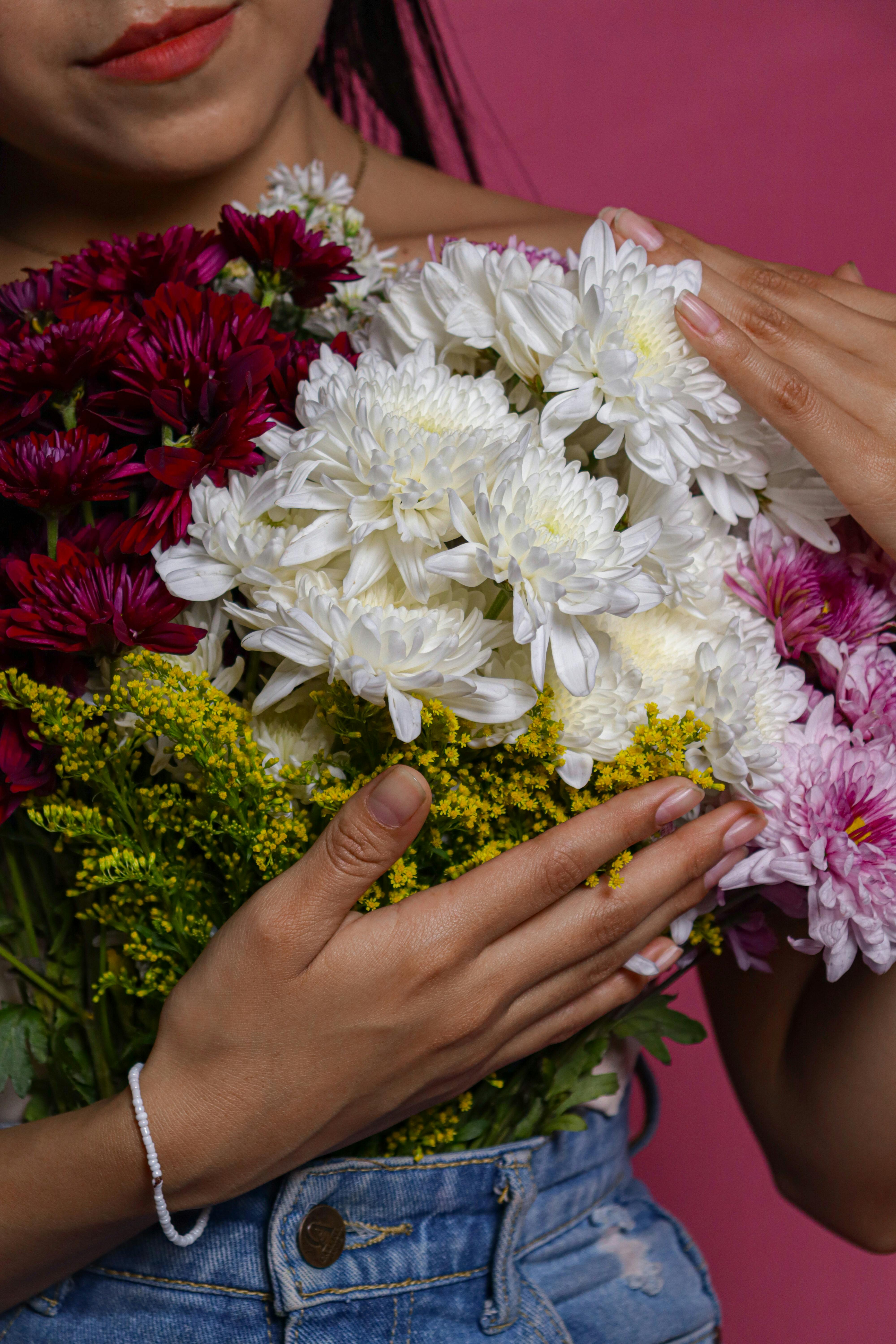 [ColoSach]-a-woman-gently-holding-a-bouquet-of-colorful-flowers-against-a-pink-background.