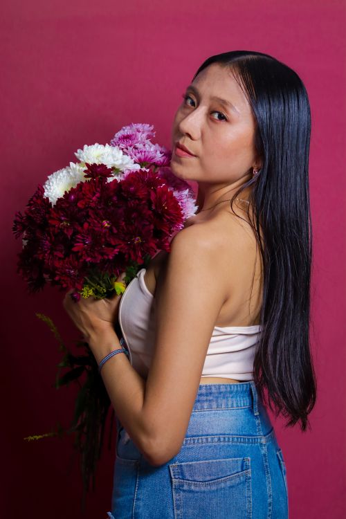 Free A woman poses with a vibrant floral bouquet against a magenta backdrop, showcasing fashion and floral beauty. Stock Photo
