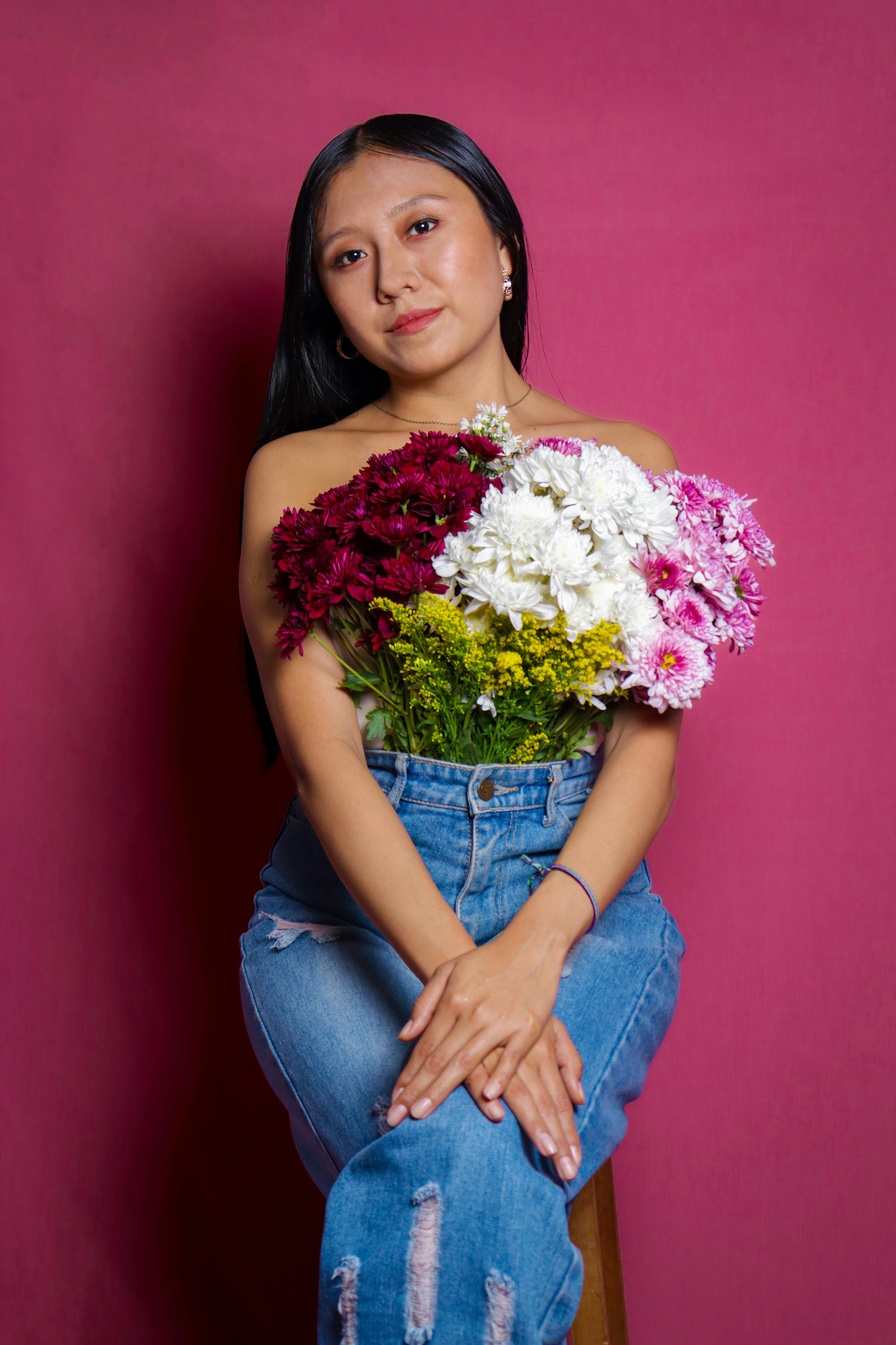 Brunette woman in studio holding vibrant flower bouquet, expressing elegance and style.