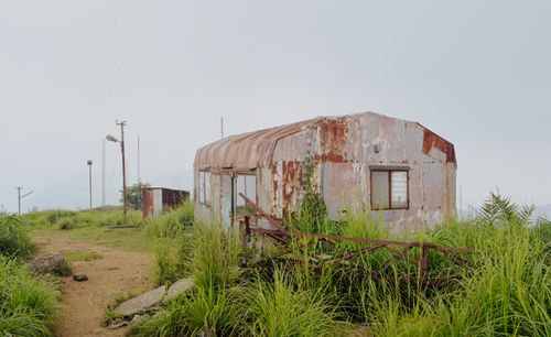 Free An abandoned rusty shed surrounded by wild grass under a misty sky, capturing decay and nature. Stock Photo