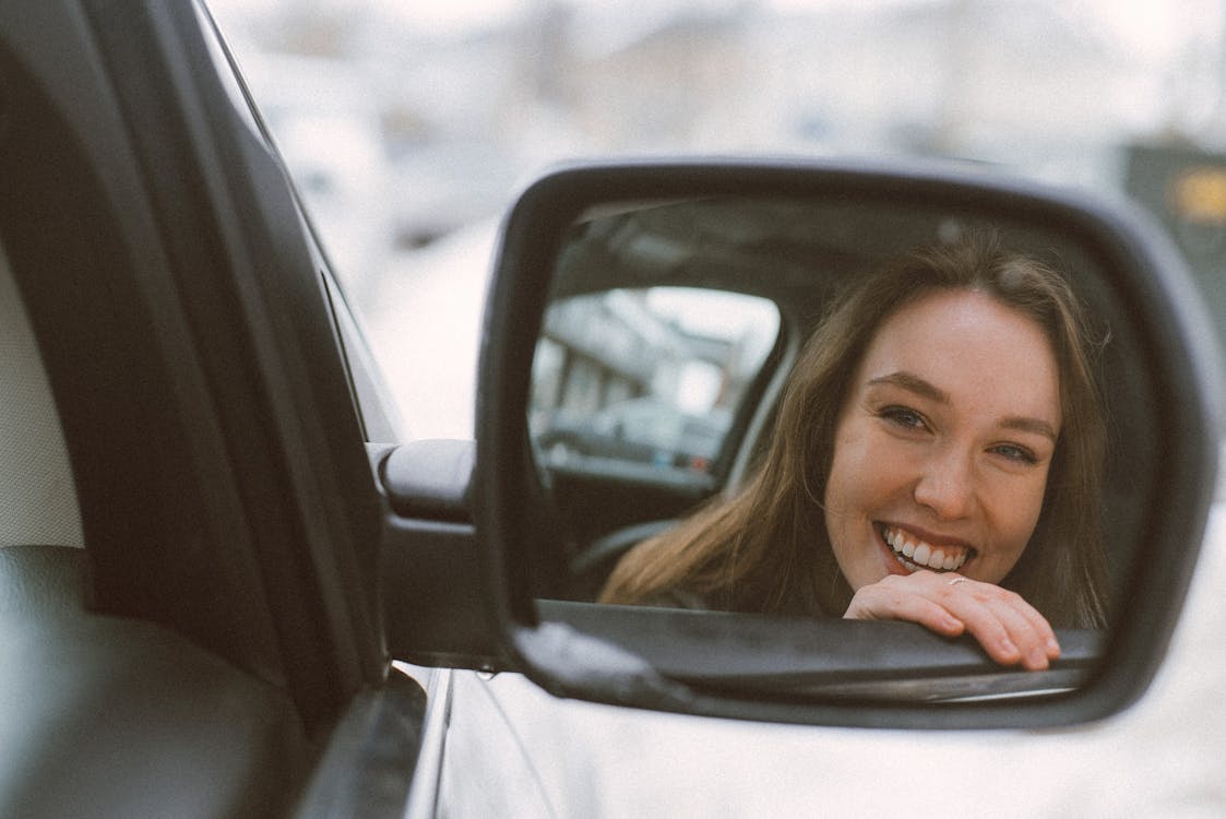 Woman Smiling Refection on Vehicle Side Mirror