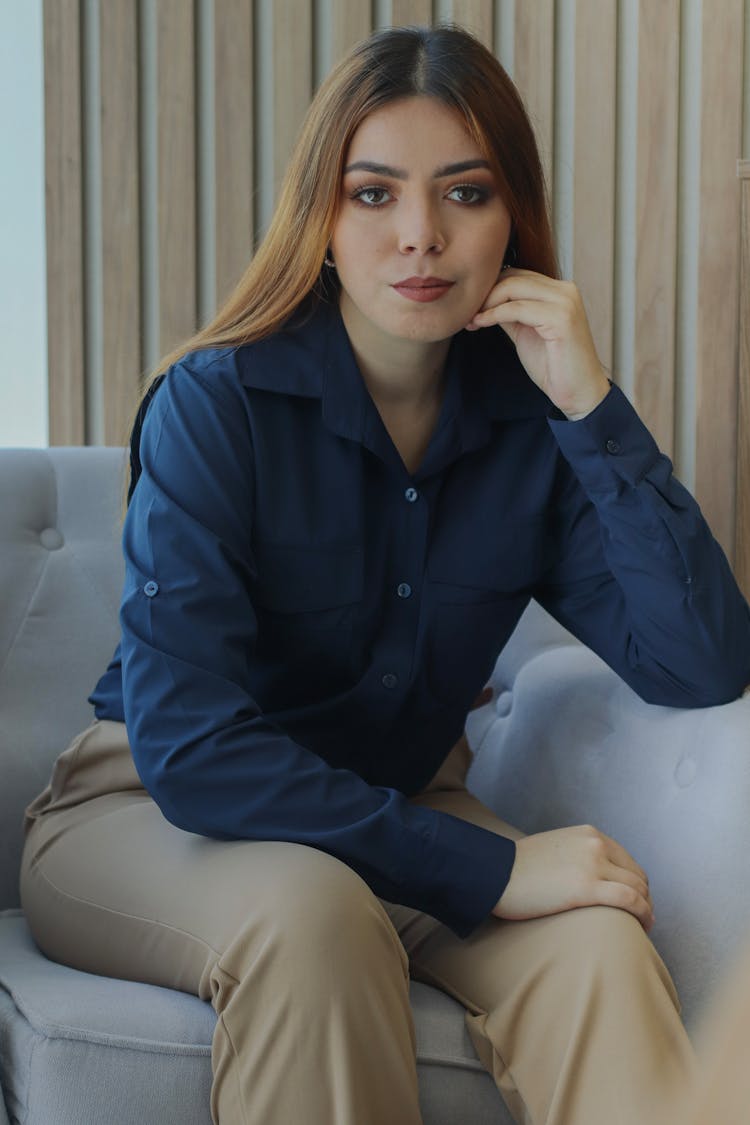 A Woman In A Blue Shirt Sitting On A Couch