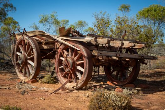 A weathered wooden cart left abandoned in a rural landscape, showcasing rustic charm.