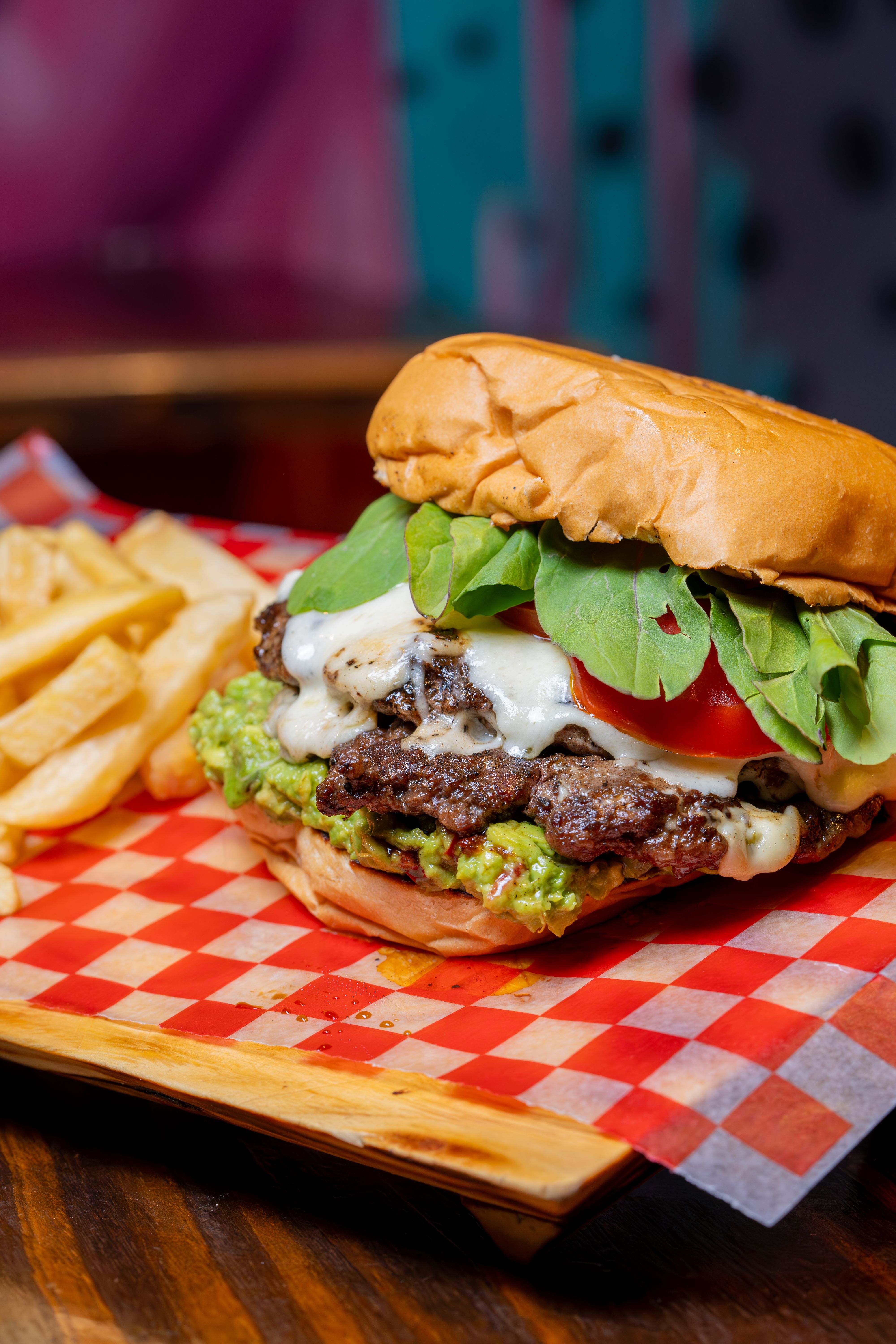Close-up of a juicy cheeseburger with toppings and crispy french fries served on a tray.