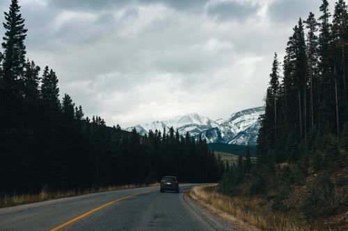 Free A car travels on a scenic highway in Kootenay Crossing, BC, Canada with mountains in the background. Stock Photo