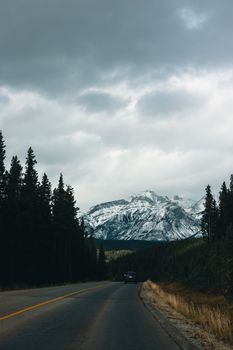 A breathtaking view of a snowy mountain range seen from a highway in Kootenay Crossing, Canada.
