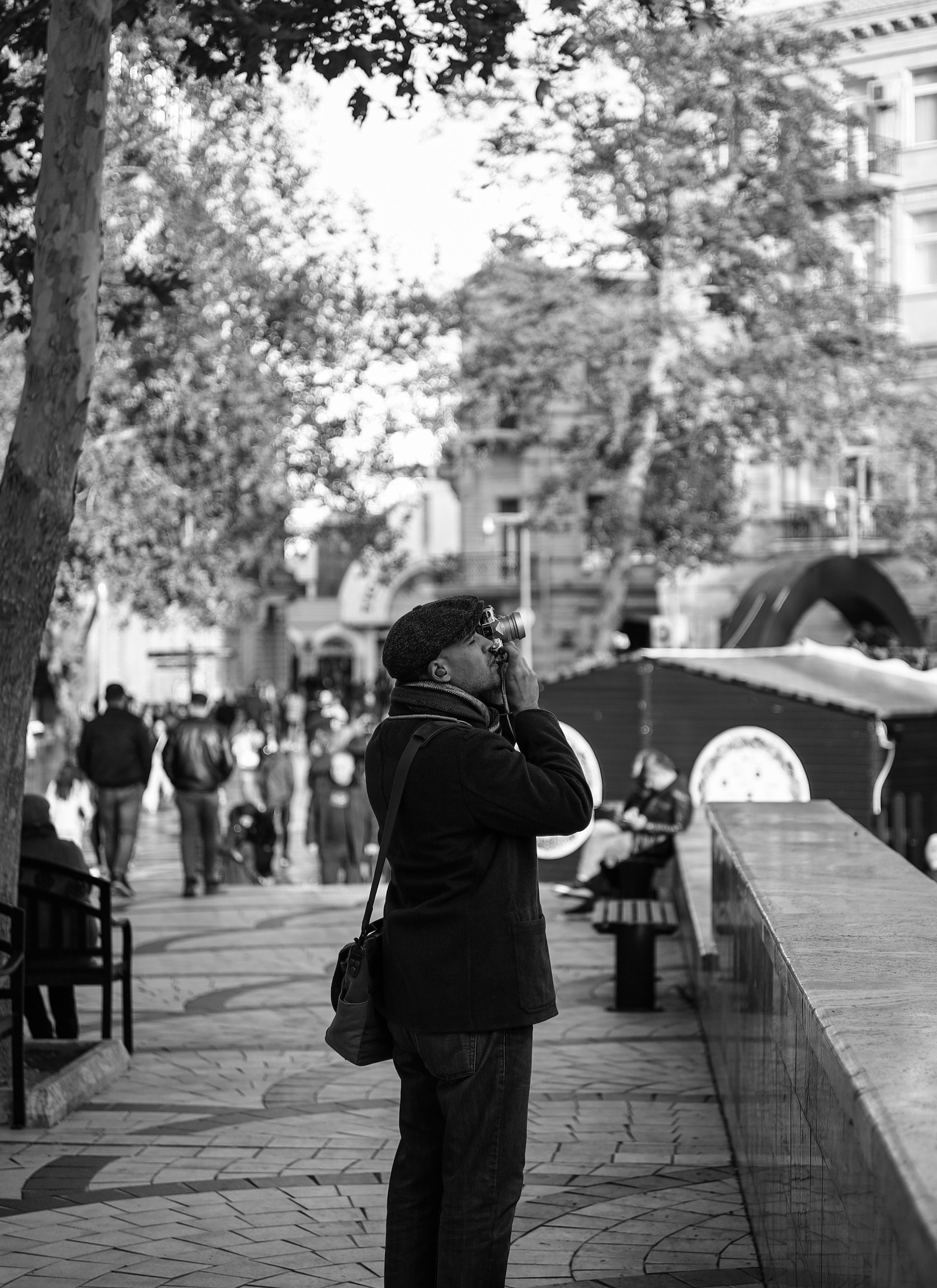 Black and white photo of a man taking pictures in bustling Baku, Azerbaijan