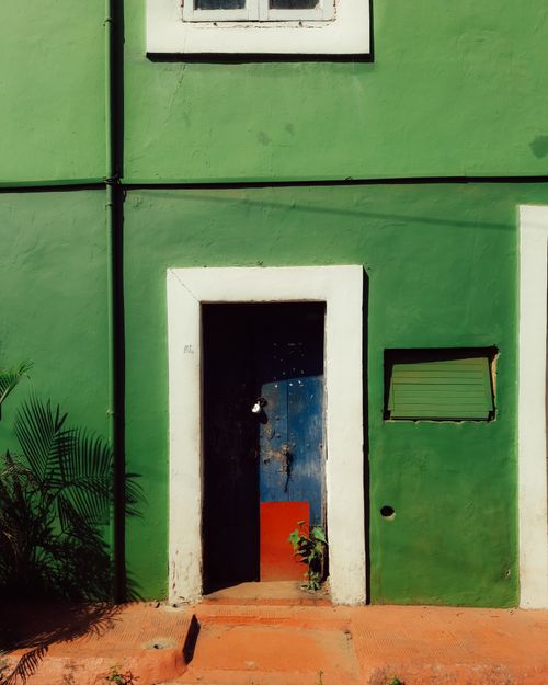 Free Vibrant facade of a green building with a blue door, capturing urban architectural charm. Stock Photo