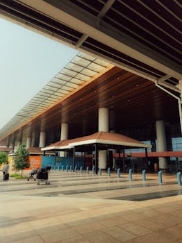 Contemporary airport entrance featuring colonnades and luggage carts, ideal for travel themes.