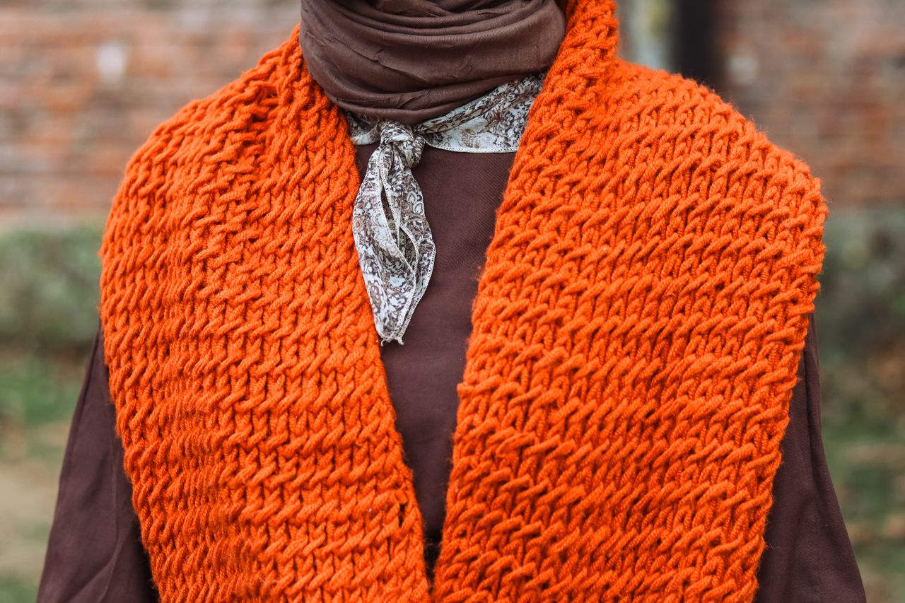 close up of a stylish orange knit scarf and brown outfit perfect for f