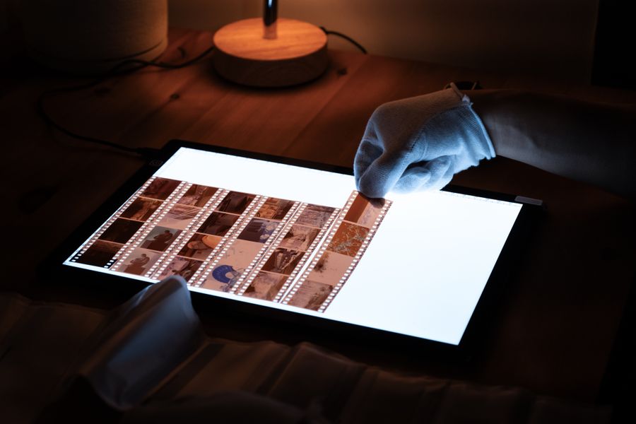 Gloved hands reviewing film negatives on a light table by Yuqi Chen on Pexels