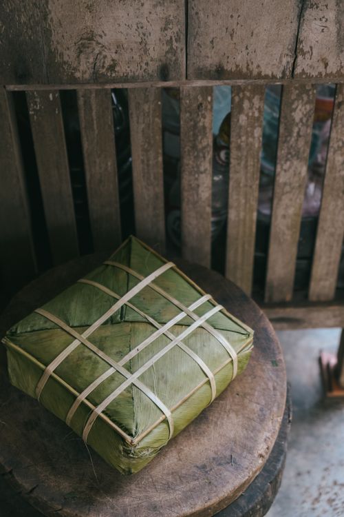 Free Square banana leaf-wrapped Banh Chung on a rustic wooden surface, representing Vietnamese culture. Stock Photo