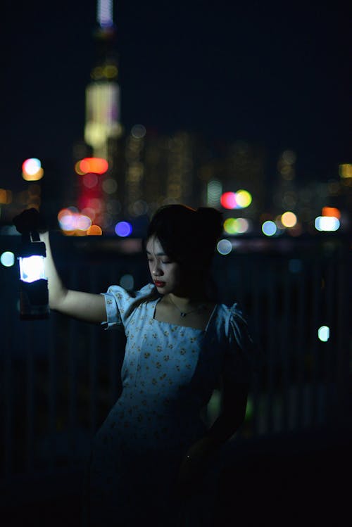 Woman Holding a Lantern on a Street at Night 