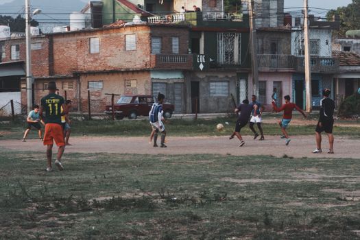 Group of young men playing football on an outdoor field in an urban neighborhood, showcasing community and sports.