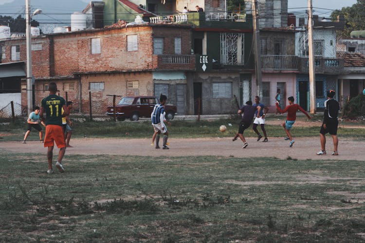 Men And Boys Playing Football On Amateur Field