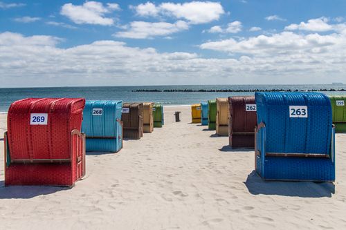 Free Vibrant beach basket chairs on sandy Helgoland beach overlooking the sea. Stock Photo