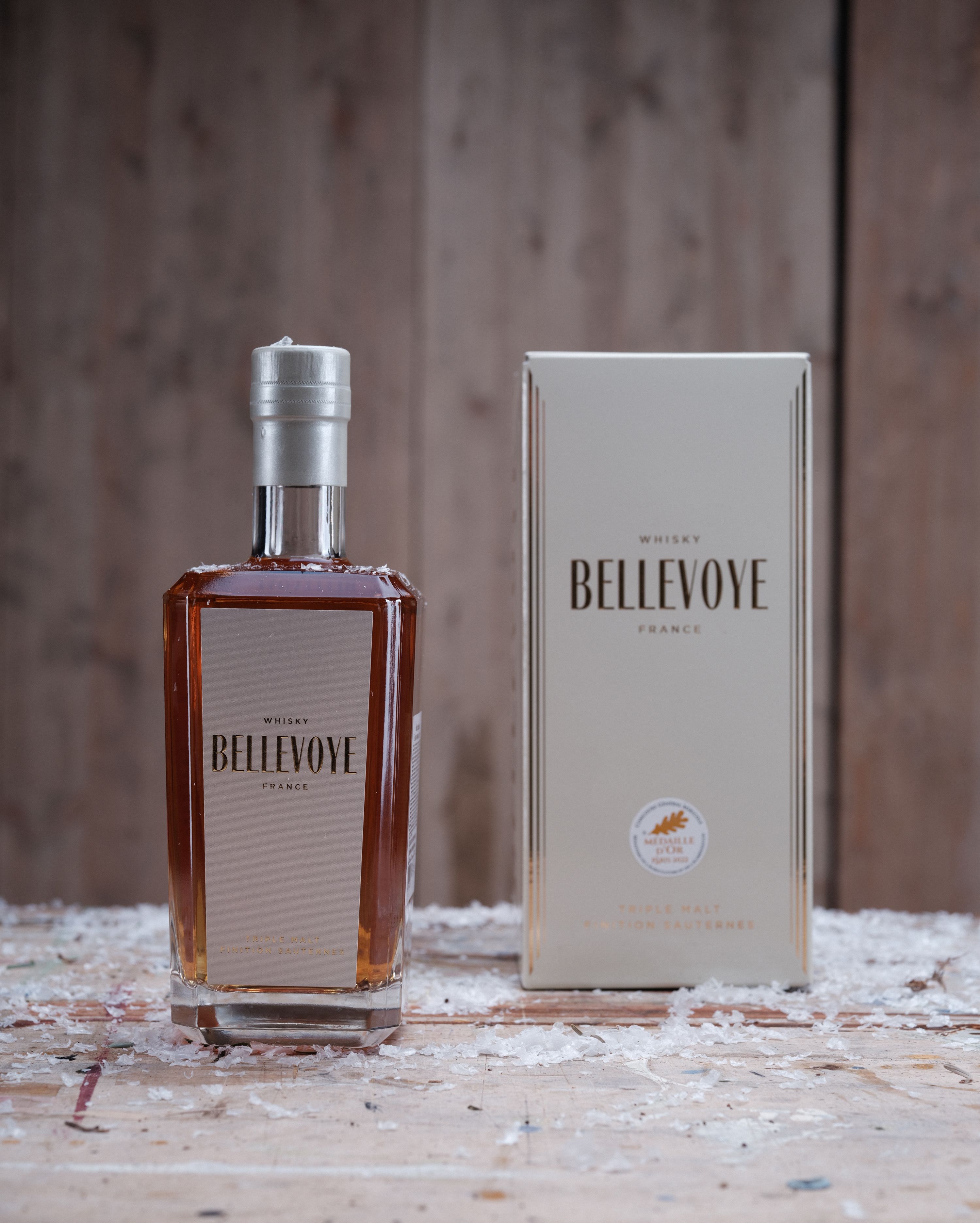 Close-up of a Bellevoye whiskey bottle and packaging on a rustic wooden table.