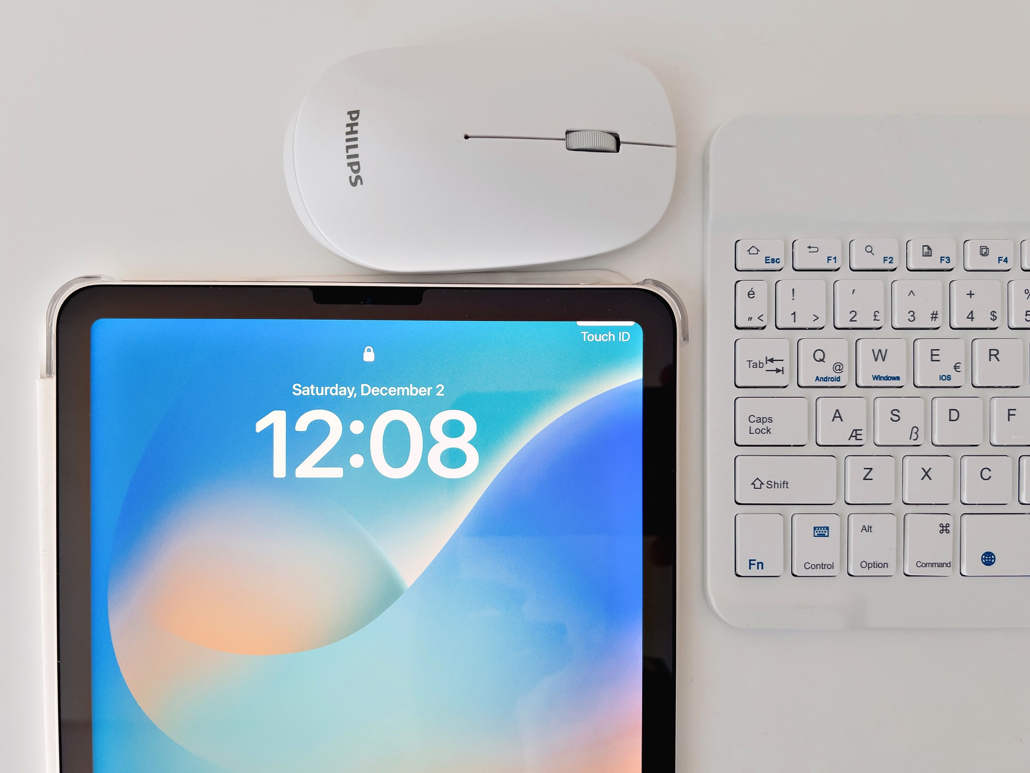Top view of a digital workspace featuring a tablet, keyboard, and mouse on a desk.