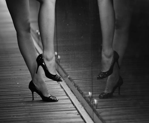 A woman's legs in high heels are reflected in a mirror