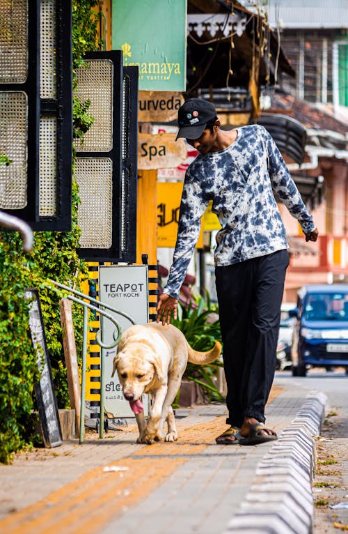 Photo of a Man Walking on the Street with a Dog 