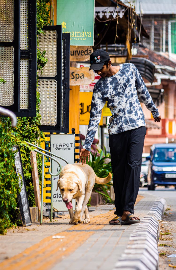 Photo Of A Man Walking On The Street With A Dog 