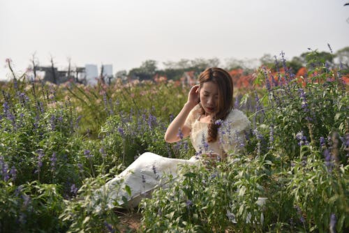Young Woman Sitting Among Lavender Flowers