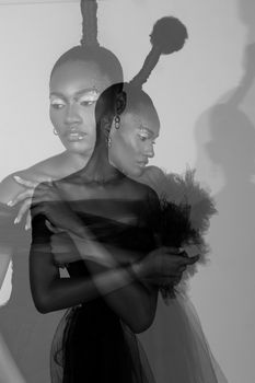 Artistic black and white fashion portrait of a woman posing with double exposure effect in a studio setting.