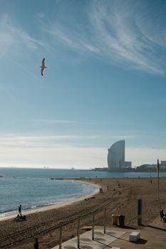 A picturesque view of Barceloneta Beach in Spain with the iconic W Hotel under a clear, sunny sky.