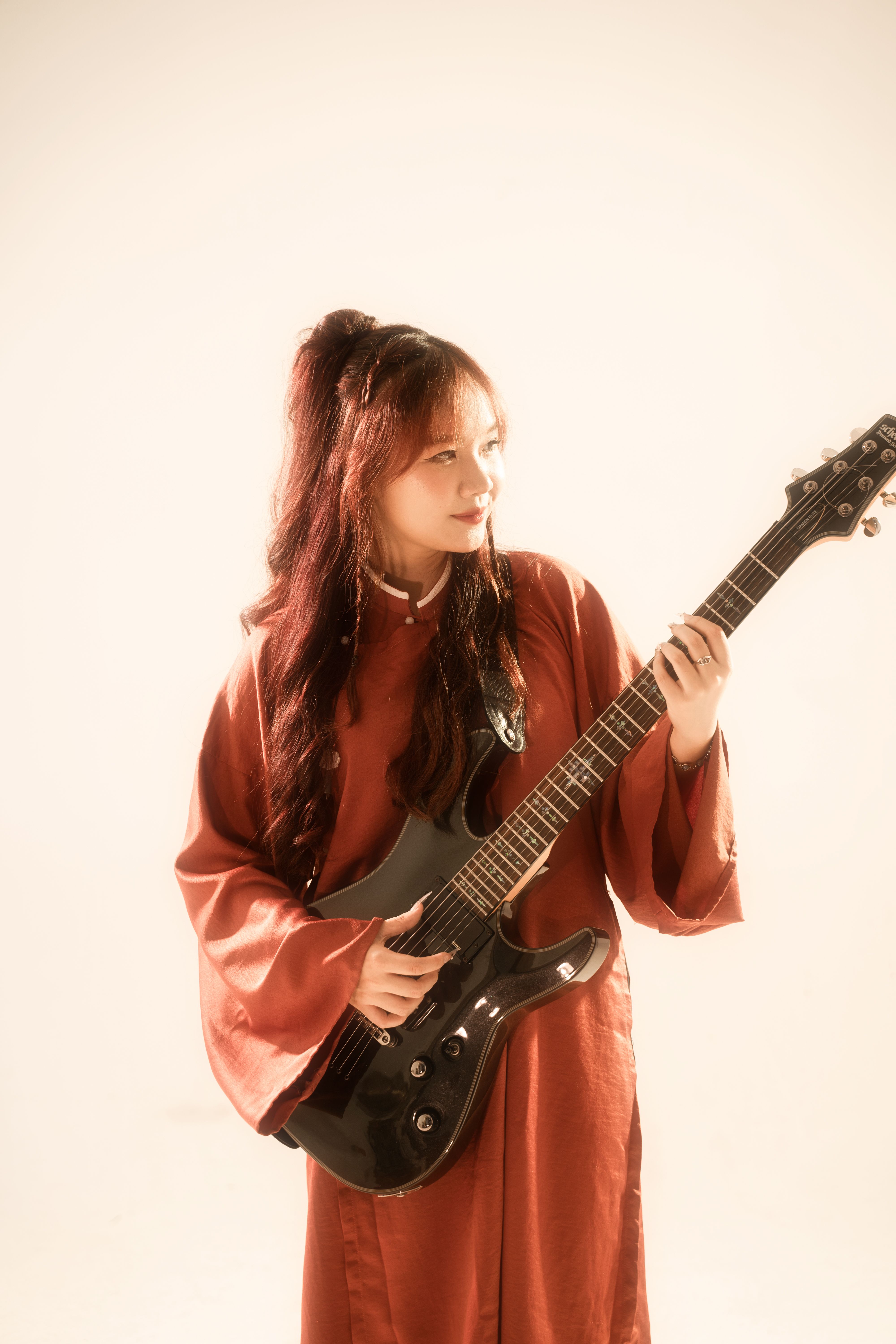 Artistic portrait of a woman playing electric guitar with soft lighting.