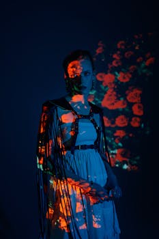 A model stands against a dark blue background with vibrant poppy projections, creating an artistic fashion portrait.