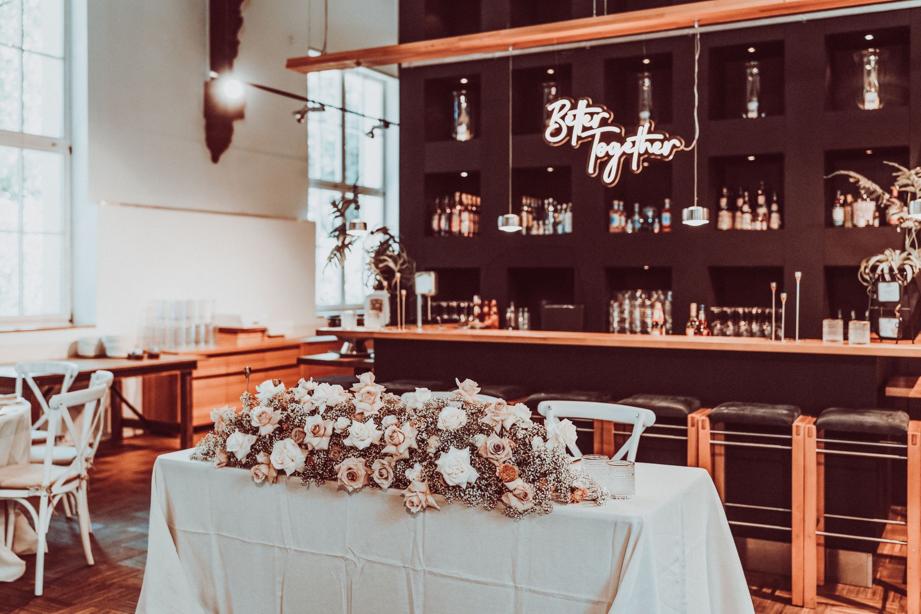 Chic wedding reception venue featuring floral decor, elegant seating, and a cozy bar environment.