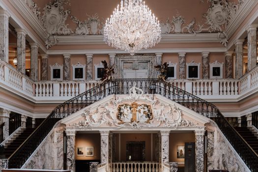 Luxurious interior of Henkell Castle featuring a grand marble staircase and ornate chandelier.