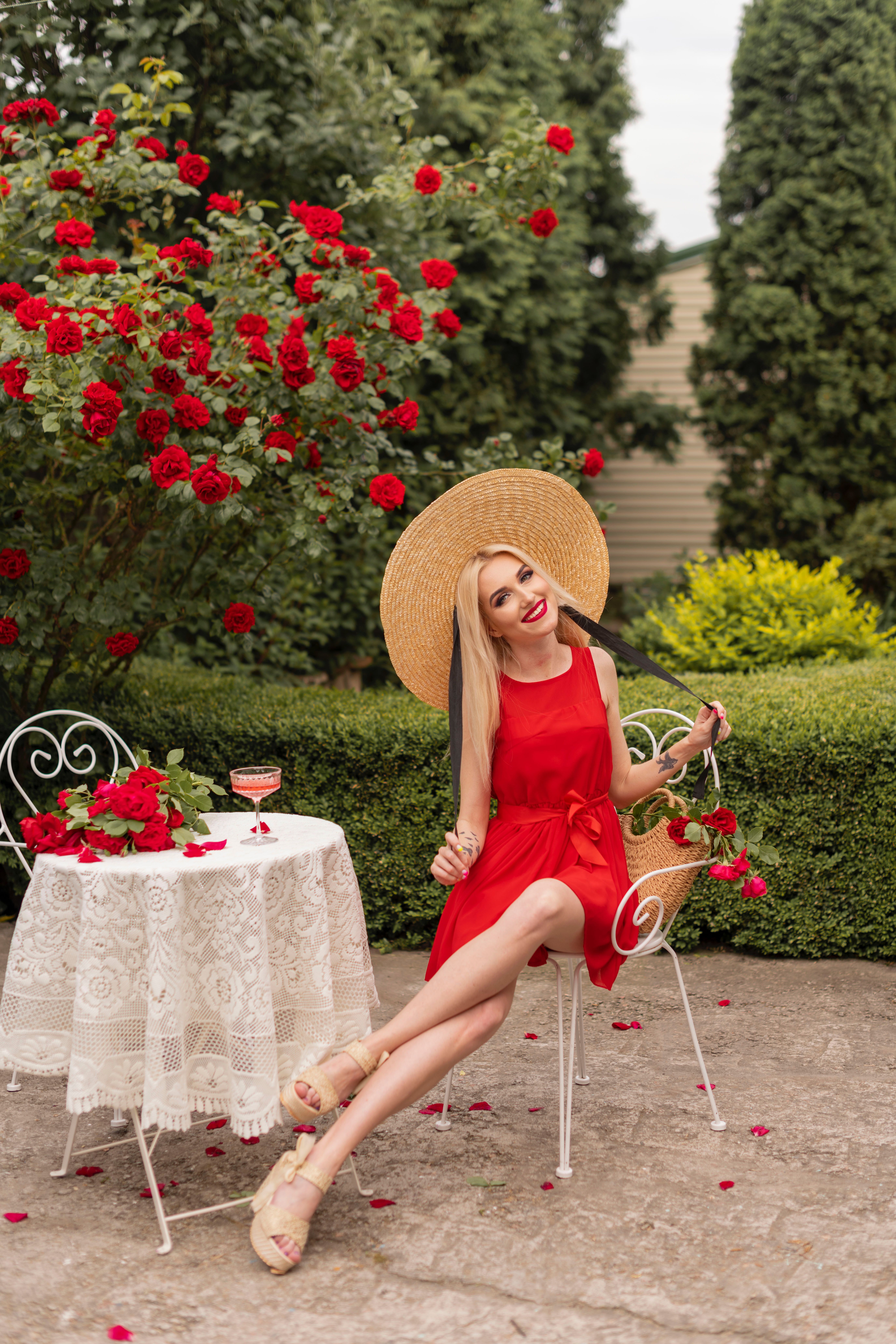 A woman in a red dress sitting on a chair in front of a table with ...