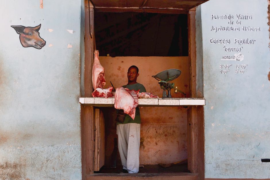 A traditional butcher shop displaying fresh meat cuts with a man at the counter.
