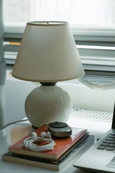 A serene desk setup featuring a cozy lamp, books, and a laptop for a minimalist aesthetic.