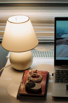 Warm and cozy home office setup featuring a lamp, laptop, and book on a desk.