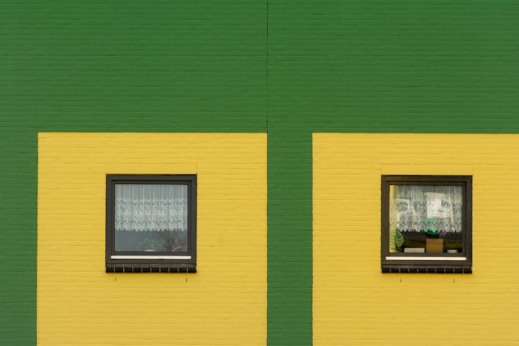 Two Windows With Green And Yellow Paint On A Building