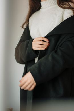 Model wearing a black wool coat over a knit sweater — photo by Berna on Pexels