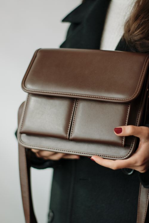 Free Close-up of a woman holding an elegant brown leather handbag, showcasing fashion and elegance. Stock Photo