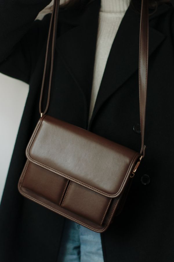 Woman in a coat carrying a brown leather bag