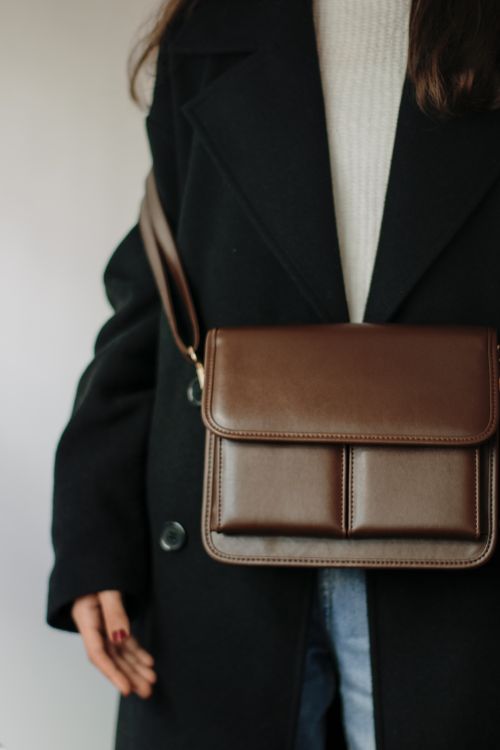 Free Stylish woman wearing a black coat and carrying a brown leather bag, showcasing modern fashion. Stock Photo