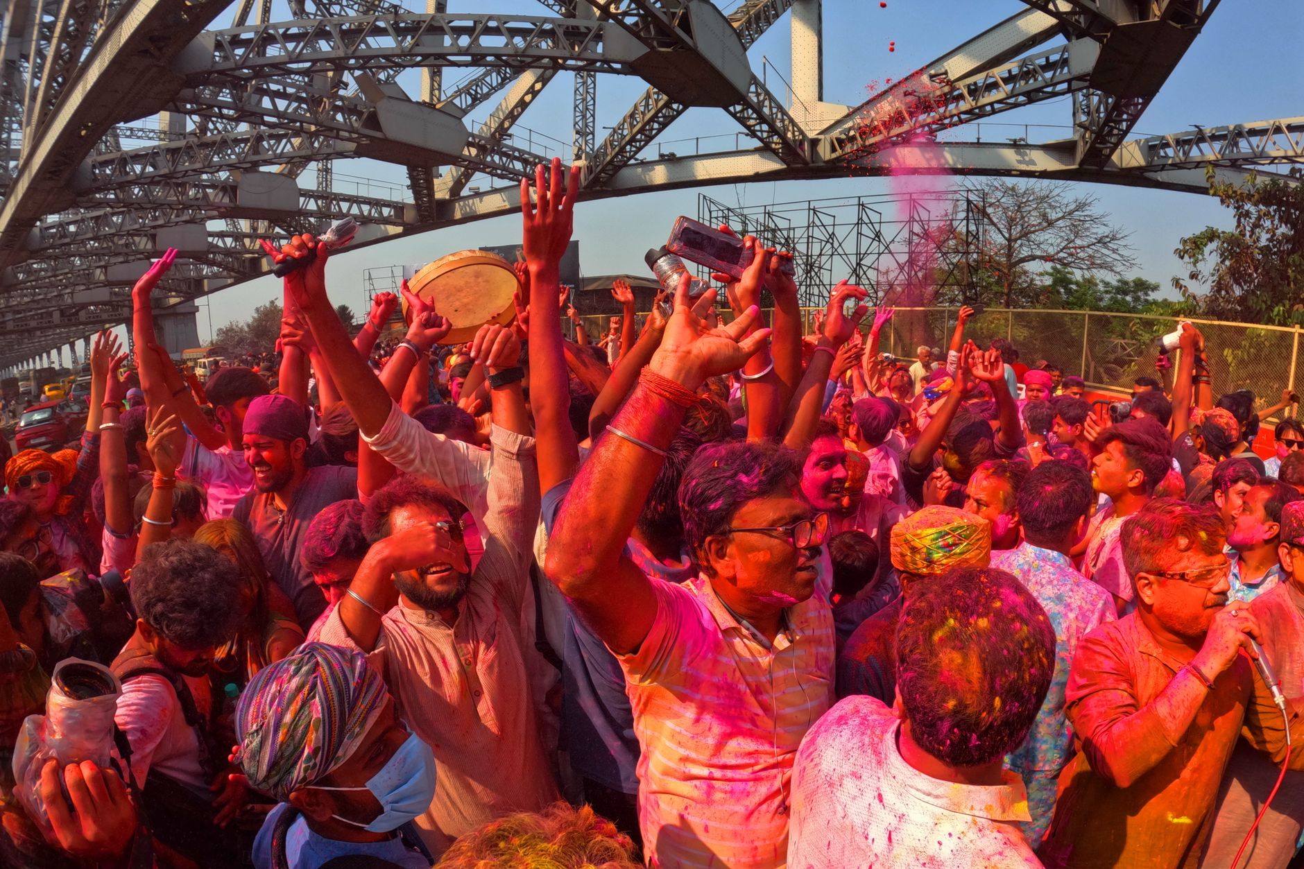 Colorful Holi festival under Howrah Bridge in Kolkata with joyful crowd.